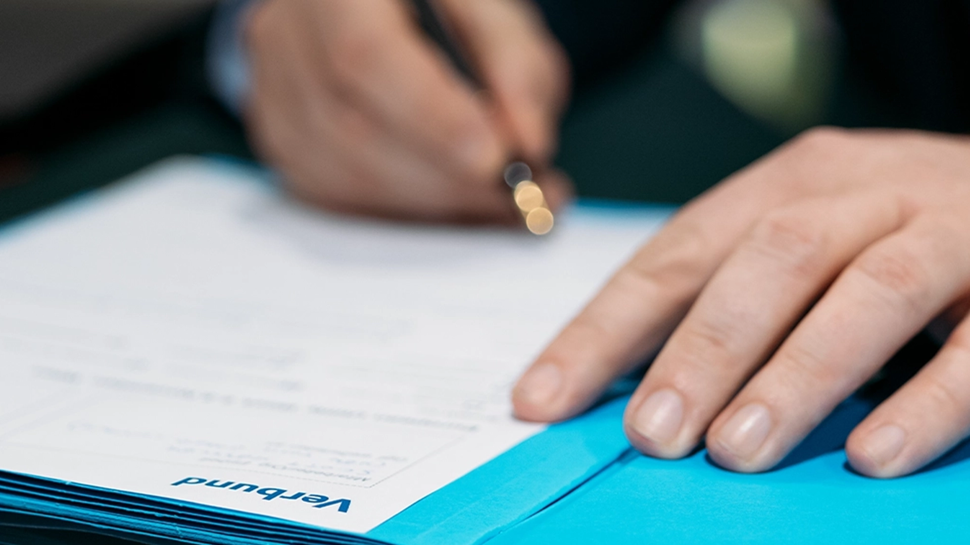 The close-up shows an open folder in blue with a document bearing the VERBUND logo.